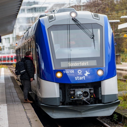 Ein Bahnmitarbeiter unterhält sich mit dem Triebwagenführer eines Alstom-Wasserstoffzugs im Bahnhof Bad Homburg.