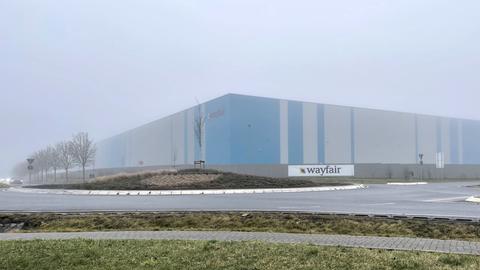 große blau-graue Lagerhalle im Nebel mit Schild von Wayfair